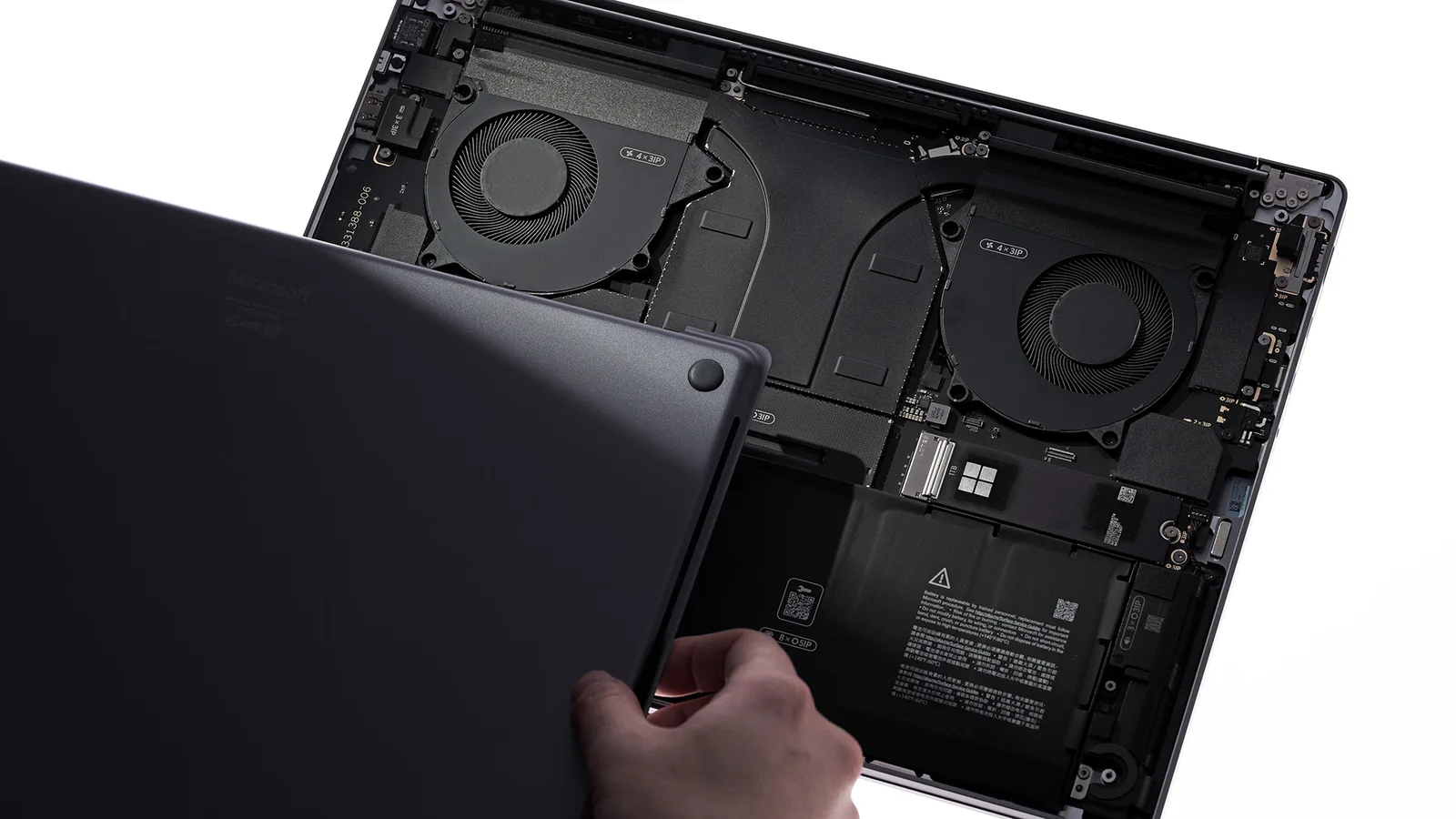 ฝาล่างของ Surface Laptop Ultra ถูกเปิดออก เห็นพัดลมสองตัว ช่อง SSD และแบตเตอรี่